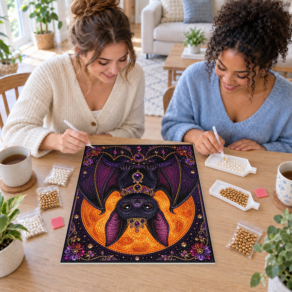Two friends creating one shared Pearl artwork — Jeweled Purple Bat Beneath a Harvest Moon. Pearl diamond painting DIY kit by Isuvio.
