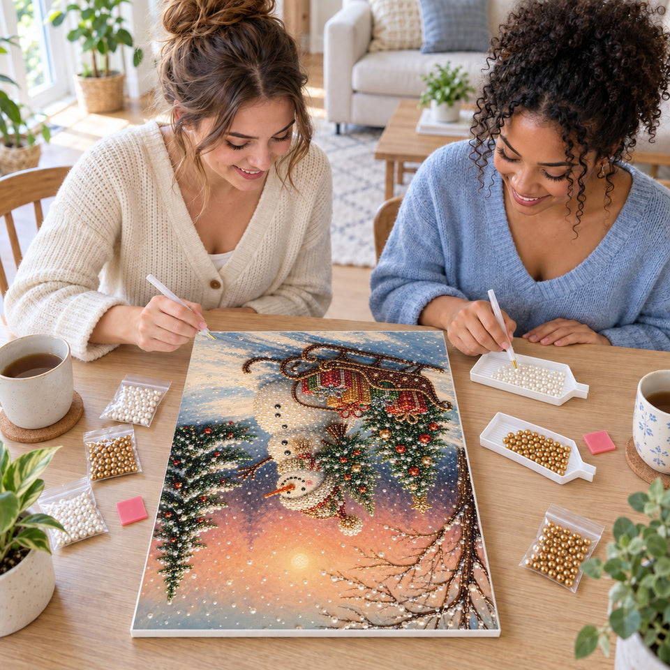 Two friends creating one shared Pearl artwork — Snowman and Gift Sleigh at Winter Sunset. Pearl diamond painting DIY kit by Isuvio.
