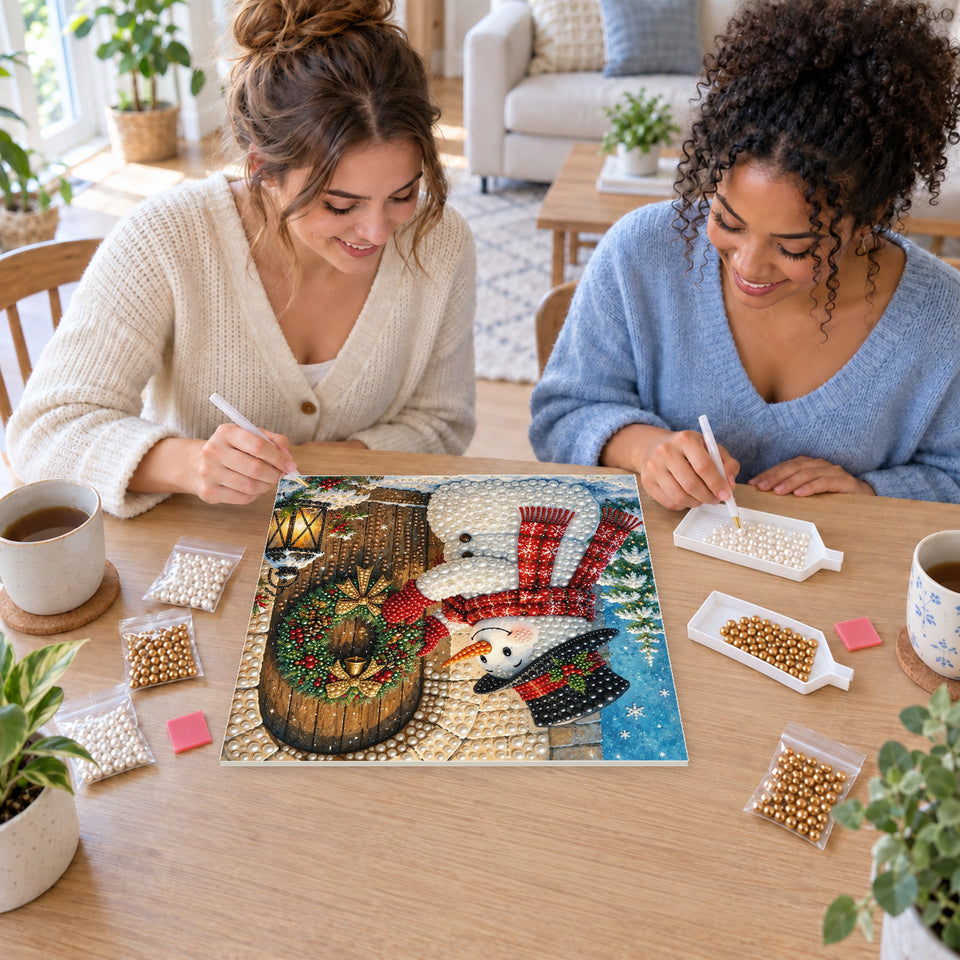 Two friends creating one shared Pearl artwork — Snowman Hanging a Christmas Wreath. Pearl diamond painting DIY kit by Isuvio.