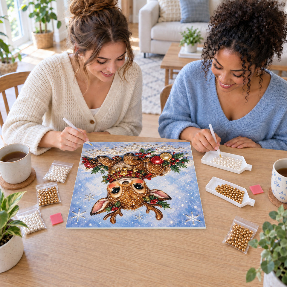 Two friends creating one shared Pearl artwork — Baby Reindeer with a Golden Star Collar. Pearl diamond painting DIY kit by Isuvio.