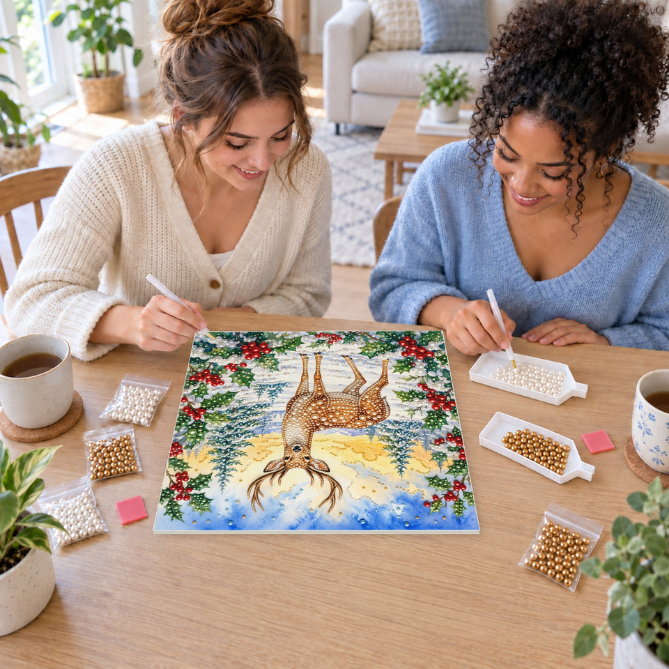 Two friends creating one shared Pearl artwork — Winter Stag beneath a Golden Sky. Pearl diamond painting DIY kit by Isuvio.