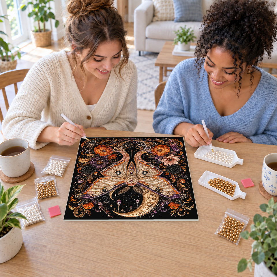 Two friends creating one shared Pearl artwork — Golden Moth Beneath a Crescent Moon and Autumn Flowers. Pearl diamond painting DIY kit by Isuvio.