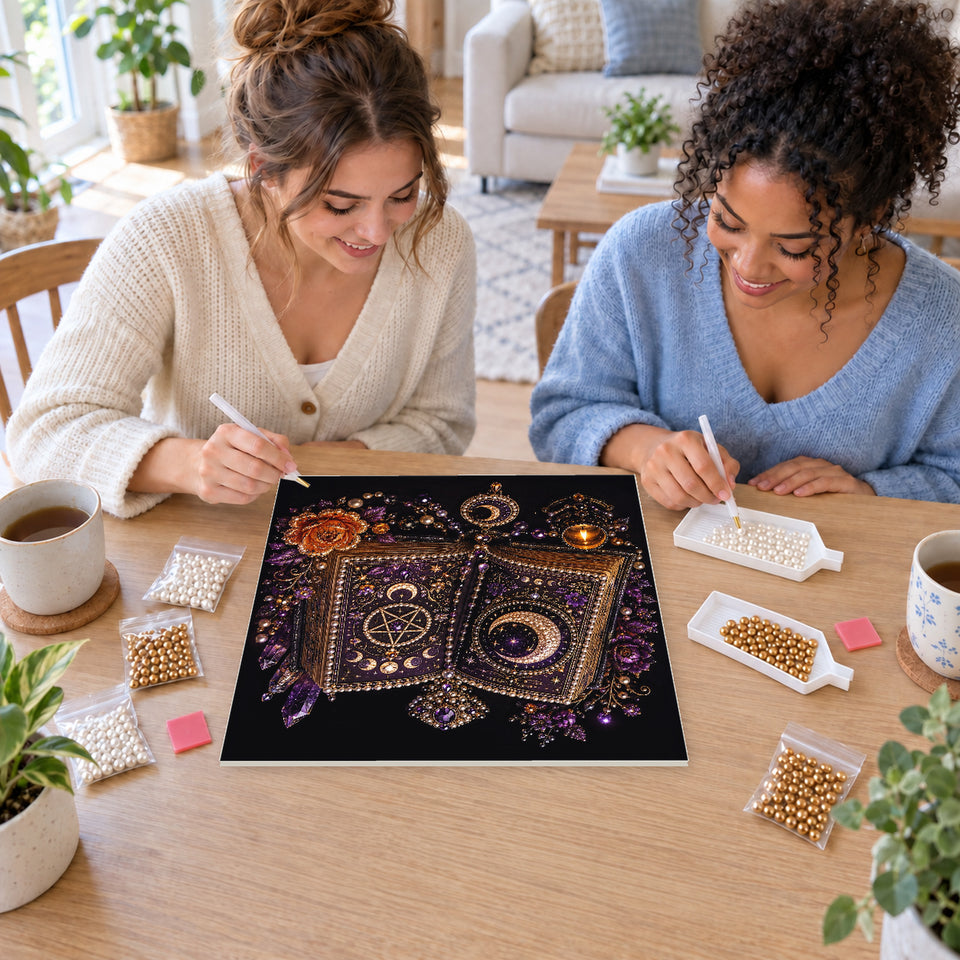 Two friends creating one shared Pearl artwork — Open Spell Book with Purple Jewels and Moon Symbols. Pearl diamond painting DIY kit by Isuvio.
