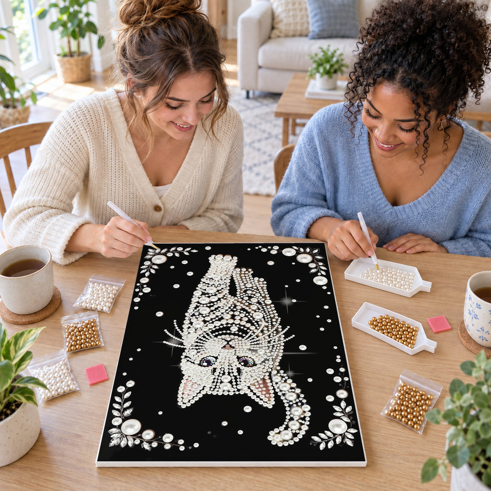 Two friends creating one shared Pearl artwork — White Pearl Cat with Blue Eyes on Black. Pearl diamond painting DIY kit by Isuvio.
