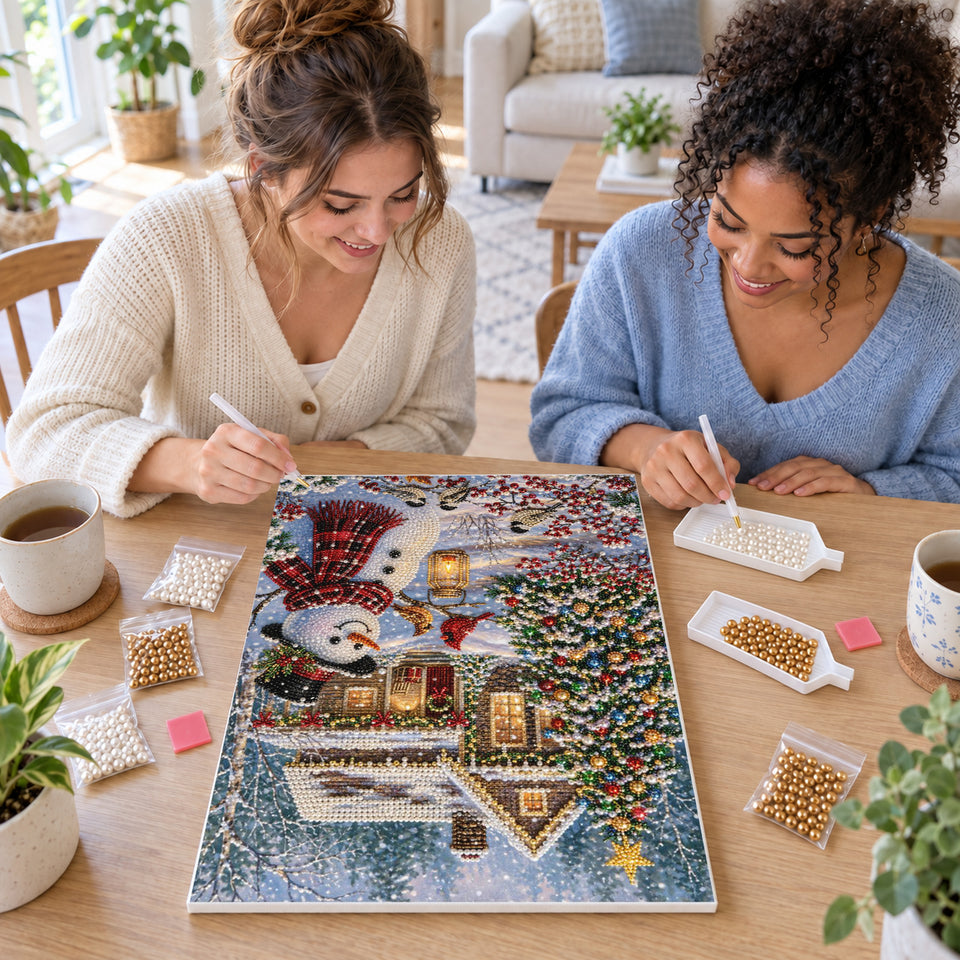 Two friends creating one shared Pearl artwork — Snowman with Cardinals Outside a Winter Cottage. Pearl diamond painting DIY kit by Isuvio.