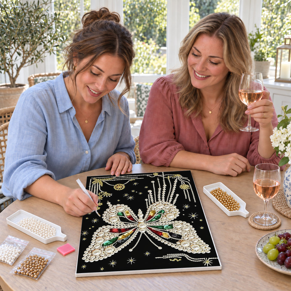 Friends enjoying a sip and craft session — White Pearl Butterfly with Colored Gems on Black. Pearl diamond painting DIY kit by Isuvio.