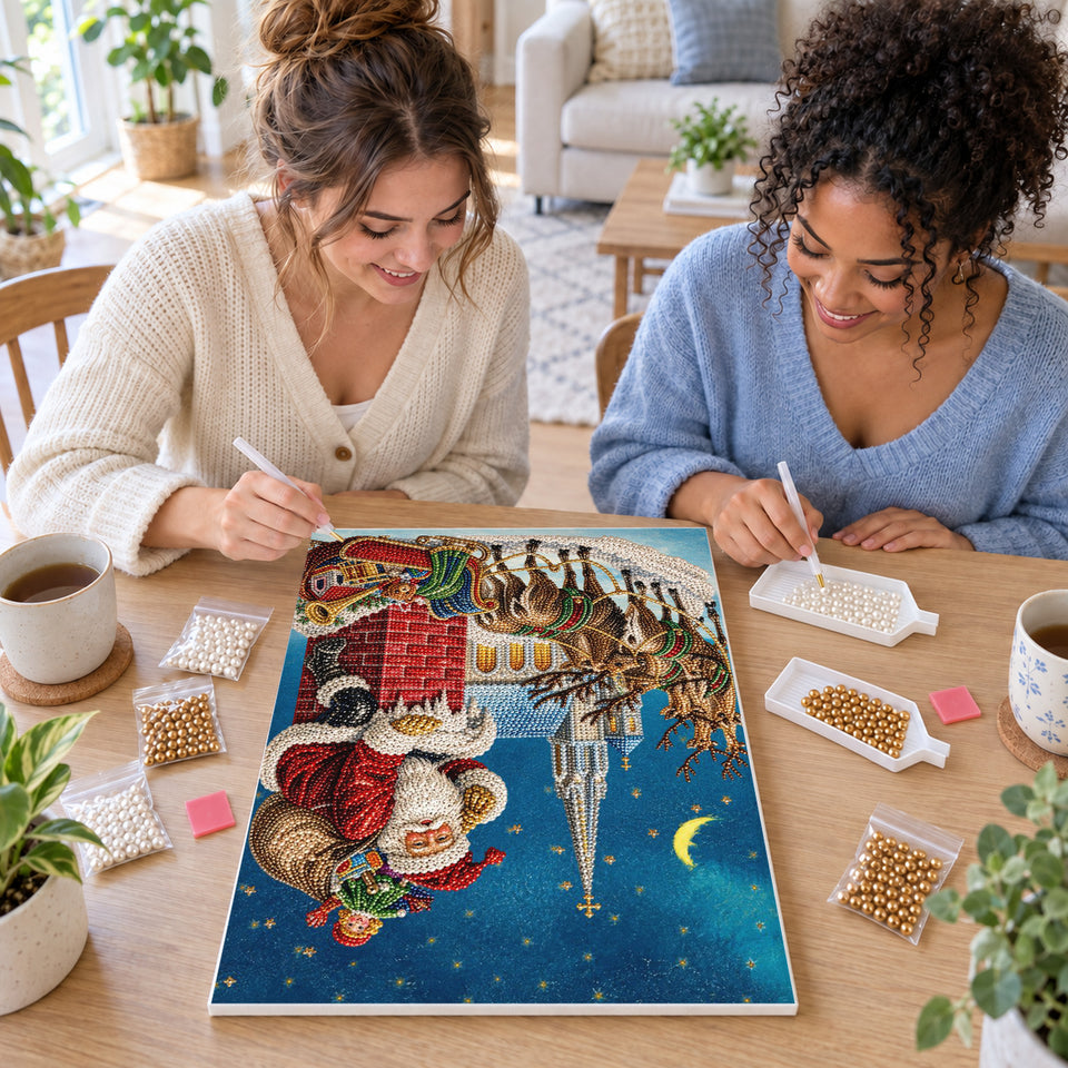 Two friends creating one shared Pearl artwork — Santa on a Chimney Above a Christmas Town. Pearl diamond painting DIY kit by Isuvio.