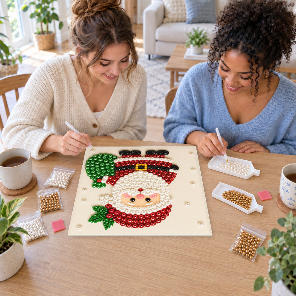 Two friends creating one shared Pearl artwork — Little Santa with a Green Gift Sack. Pearl diamond painting DIY kit by Isuvio.