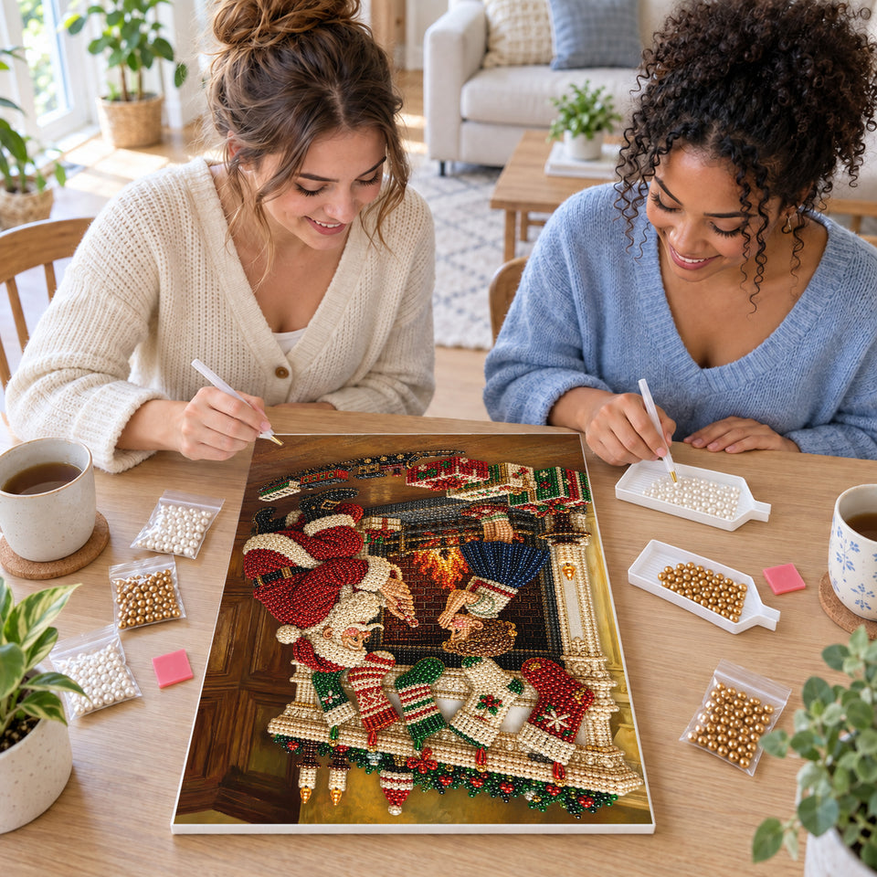 Two friends creating one shared Pearl artwork — Santa and a Child Beside the Christmas Fireplace. Pearl diamond painting DIY kit by Isuvio.