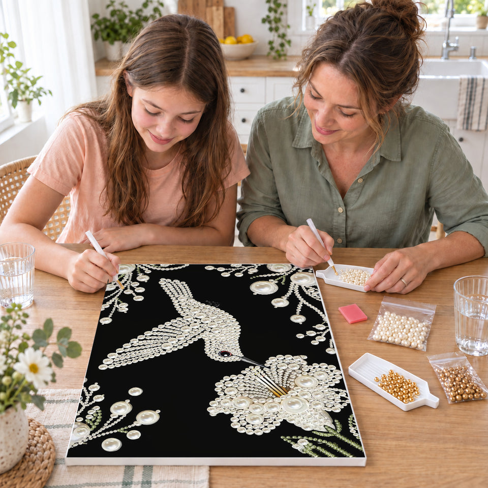Mother and daughter creating one shared Pearl artwork — White Pearl Hummingbird and Blossom on Black. Pearl diamond painting DIY kit by Isuvio.