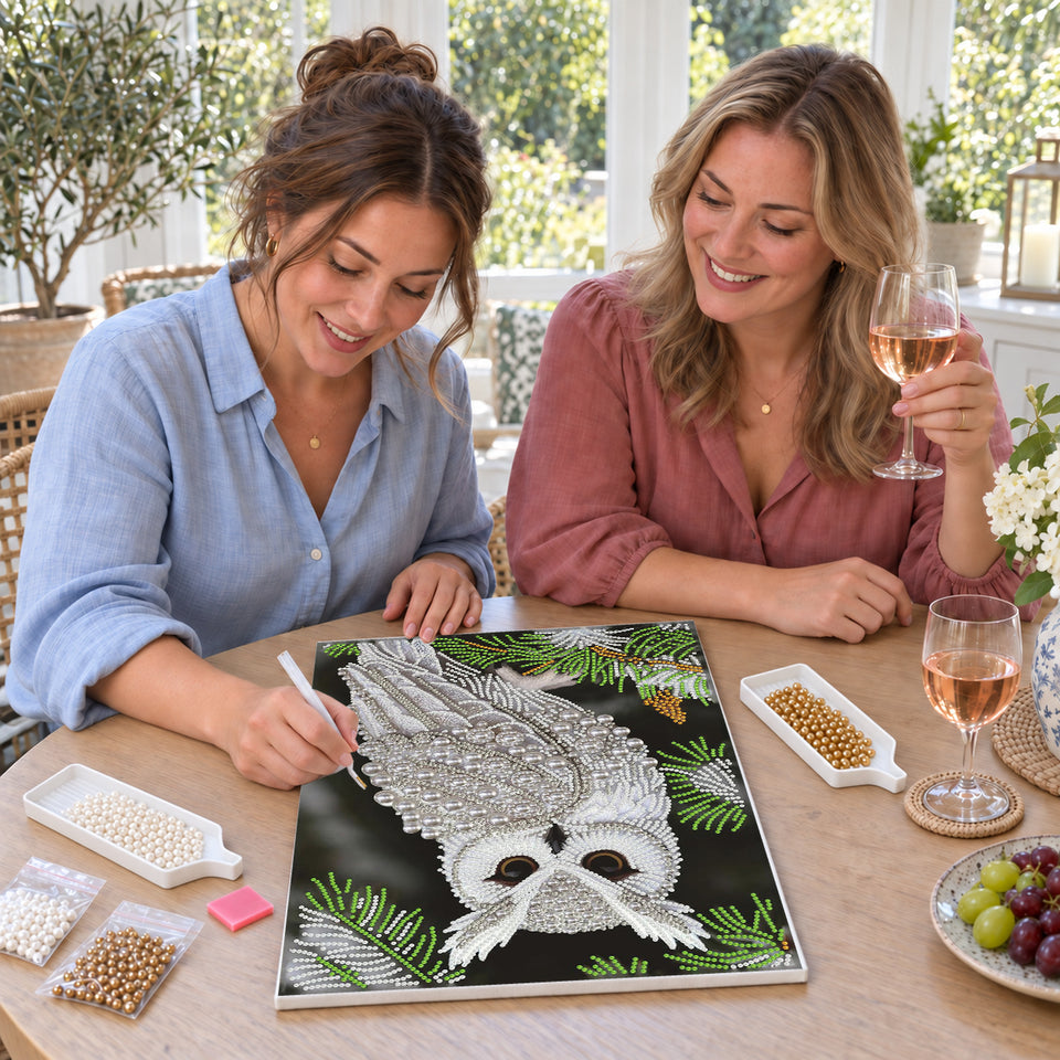 Friends enjoying a sip and craft session — White Owl Among Evergreen Branches. Pearl diamond painting DIY kit by Isuvio.