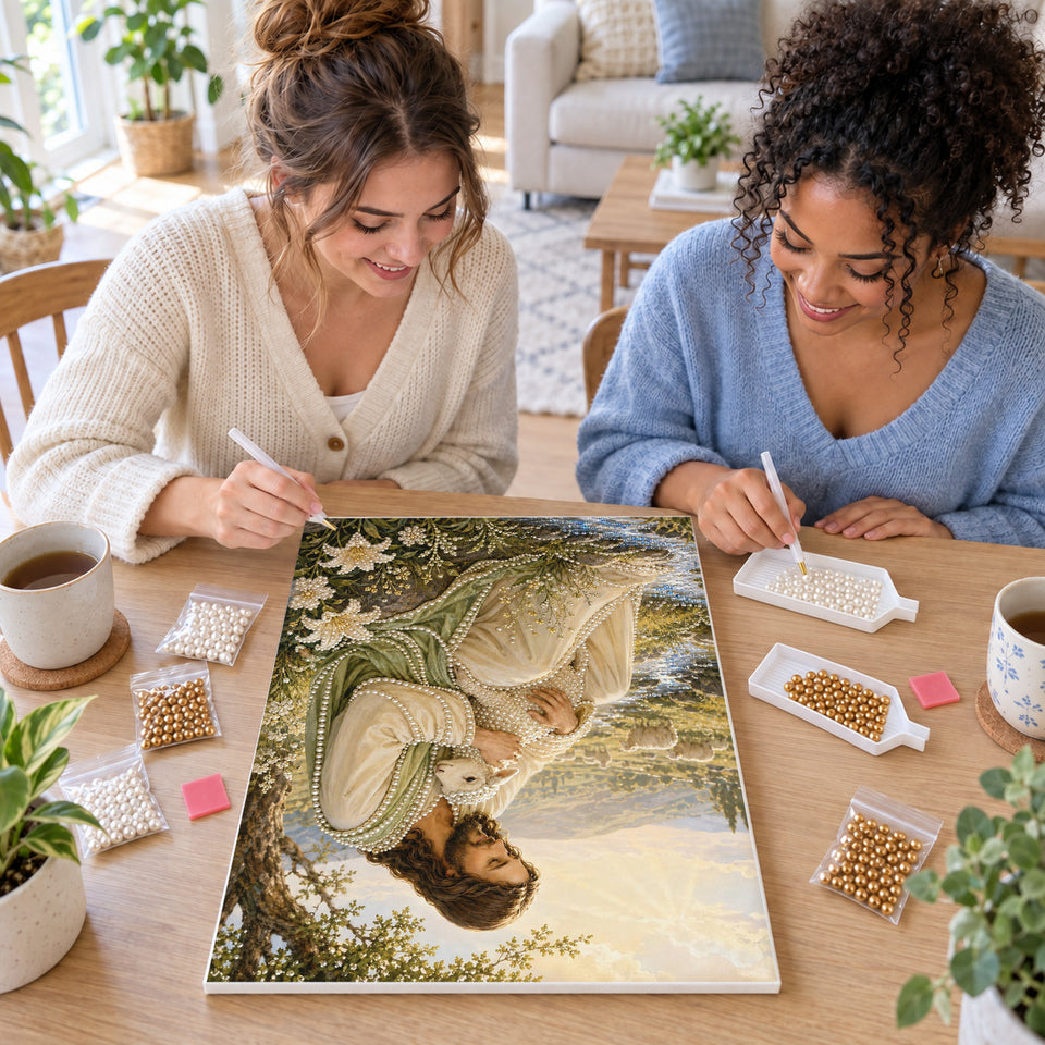 Two friends creating one shared Pearl artwork — Jesus Holding a Lamb Beside a Peaceful Stream. Pearl diamond painting DIY kit by Isuvio.