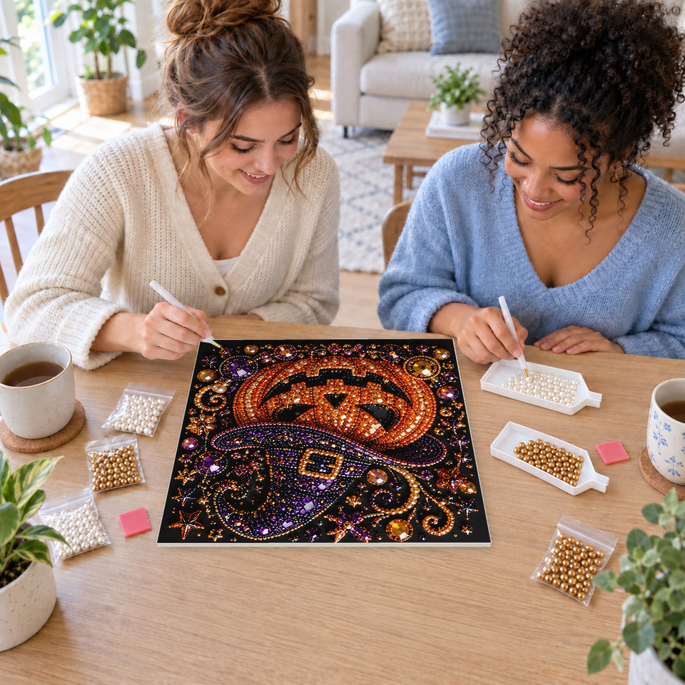 Two friends creating one shared Pearl artwork — Grinning Pumpkin in a Purple Witch Hat. Pearl diamond painting DIY kit by Isuvio.