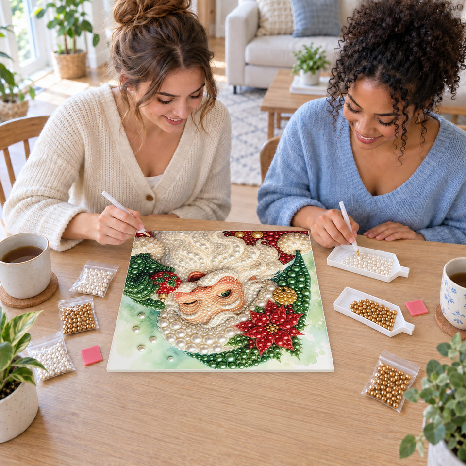 Two friends creating one shared Pearl artwork — Green-Hatted Santa with a Red Poinsettia. Pearl diamond painting DIY kit by Isuvio.