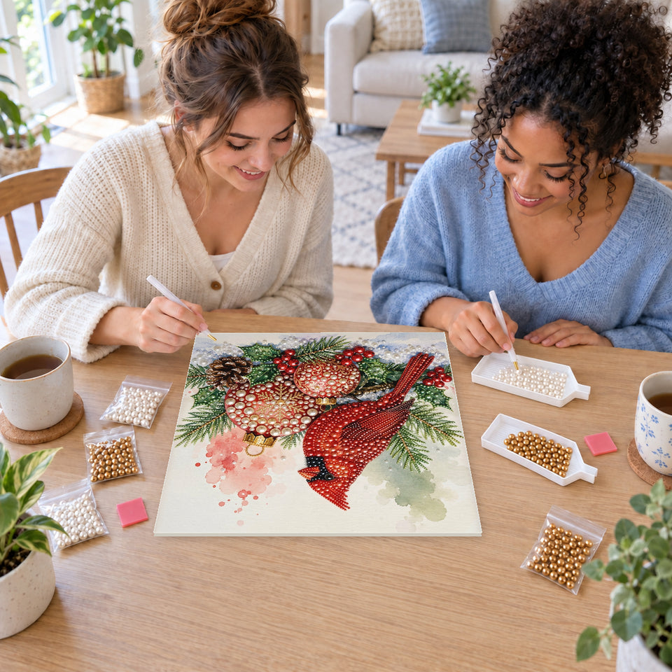 Two friends creating one shared Pearl artwork — Cardinal with Red and Gold Christmas Baubles. Pearl diamond painting DIY kit by Isuvio.