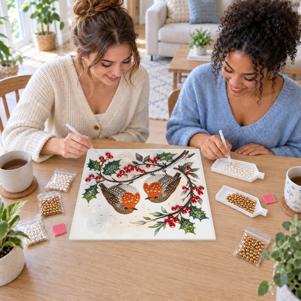 Two friends creating one shared Pearl artwork — Two Robins on Christmas Holly. Pearl diamond painting DIY kit by Isuvio.