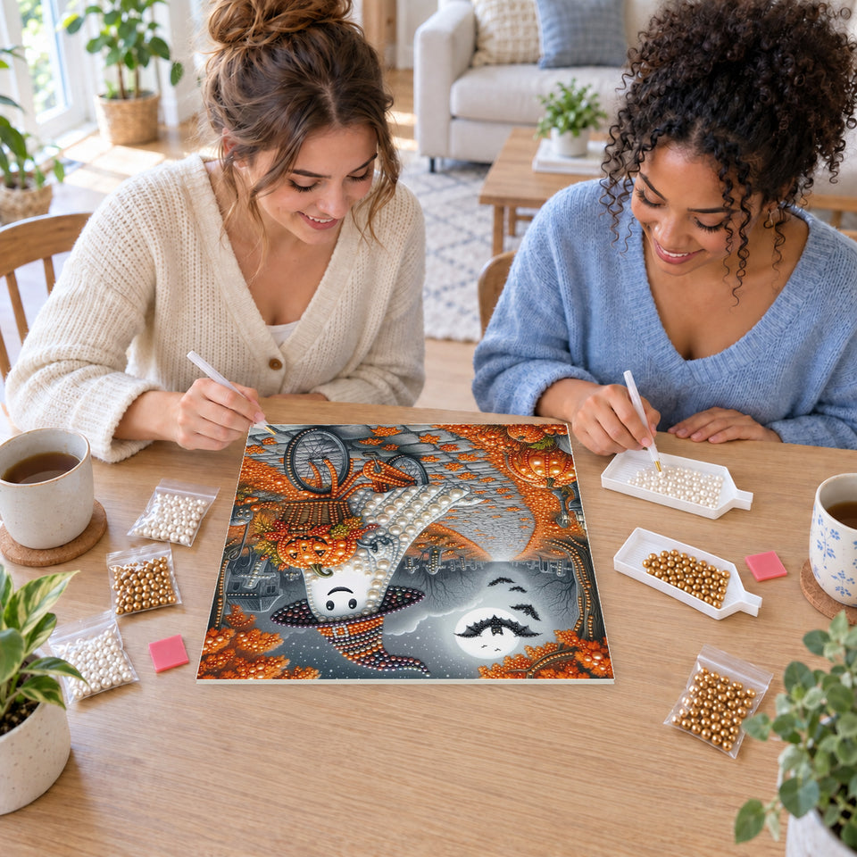 Two friends creating one shared Pearl artwork — Bicycle Ghost with a Basket of Pumpkins. Pearl diamond painting DIY kit by Isuvio.