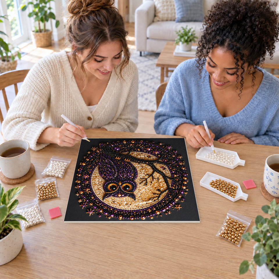 Two friends creating one shared Pearl artwork — Purple Owl in a Golden Moon Medallion. Pearl diamond painting DIY kit by Isuvio.