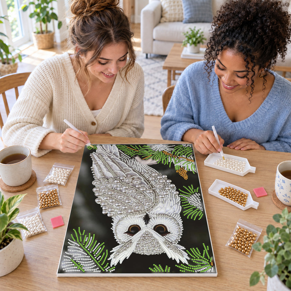 Two friends creating one shared Pearl artwork — White Owl Among Evergreen Branches. Pearl diamond painting DIY kit by Isuvio.