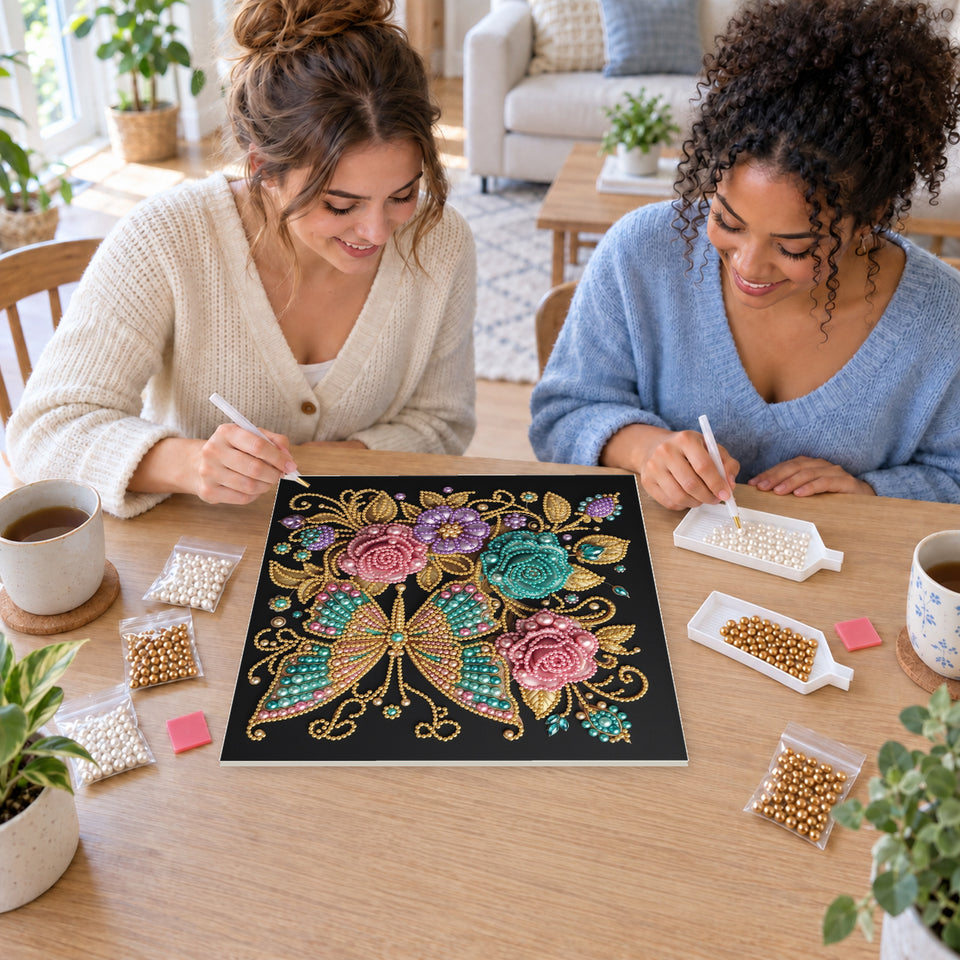 Two friends creating one shared Pearl artwork — Jewel Butterfly with Pink and Teal Roses. Pearl diamond painting DIY kit by Isuvio.
