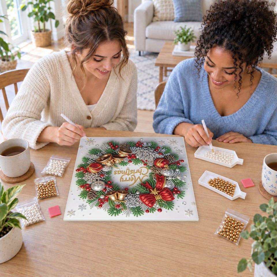 Two friends creating one shared Pearl artwork — Merry Christmas Wreath with Red Bows and Golden Bells. Pearl diamond painting DIY kit by Isuvio.