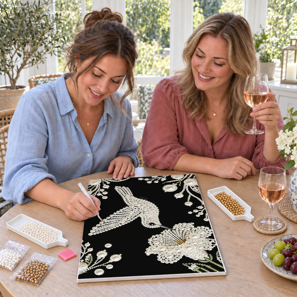 Friends enjoying a sip and craft session — White Pearl Hummingbird and Blossom on Black. Pearl diamond painting DIY kit by Isuvio.