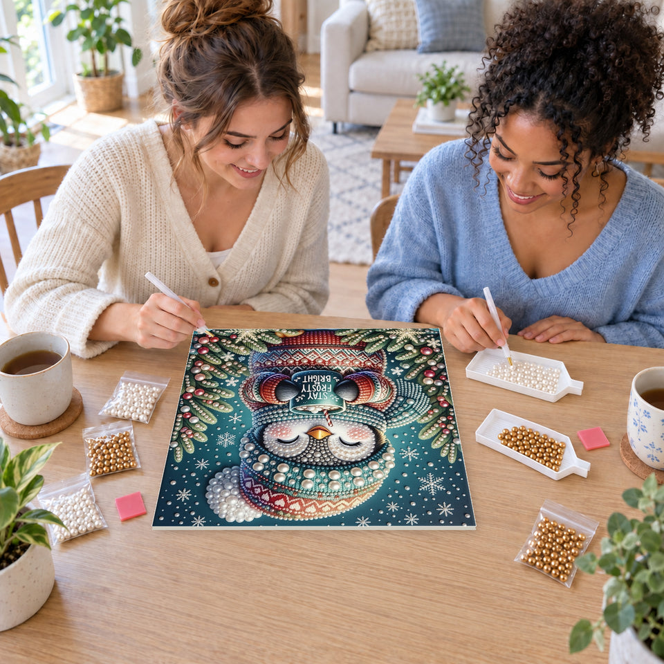 Two friends creating one shared Pearl artwork — Stay Frosty Penguin with a Cocoa Mug. Pearl diamond painting DIY kit by Isuvio.