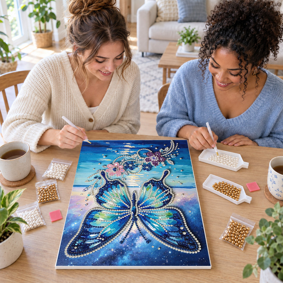 Two friends creating one shared Pearl artwork — Blue Butterfly Above Ocean Waves and Flowers. Pearl diamond painting DIY kit by Isuvio.