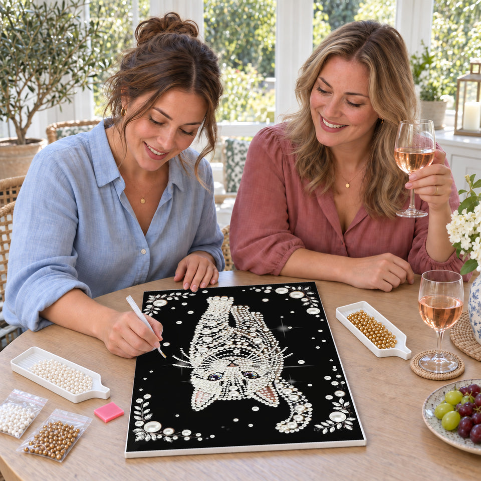 Friends enjoying a sip and craft session — White Pearl Cat with Blue Eyes on Black. Pearl diamond painting DIY kit by Isuvio.