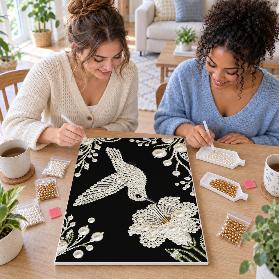 Two friends creating one shared Pearl artwork — White Pearl Hummingbird and Blossom on Black. Pearl diamond painting DIY kit by Isuvio.