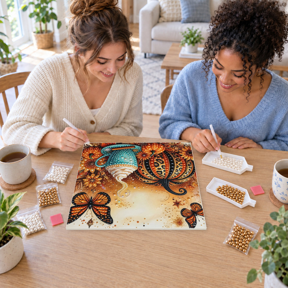 Two friends creating one shared Pearl artwork — Autumn Pumpkin with a Teal Mug and Butterflies. Pearl diamond painting DIY kit by Isuvio.