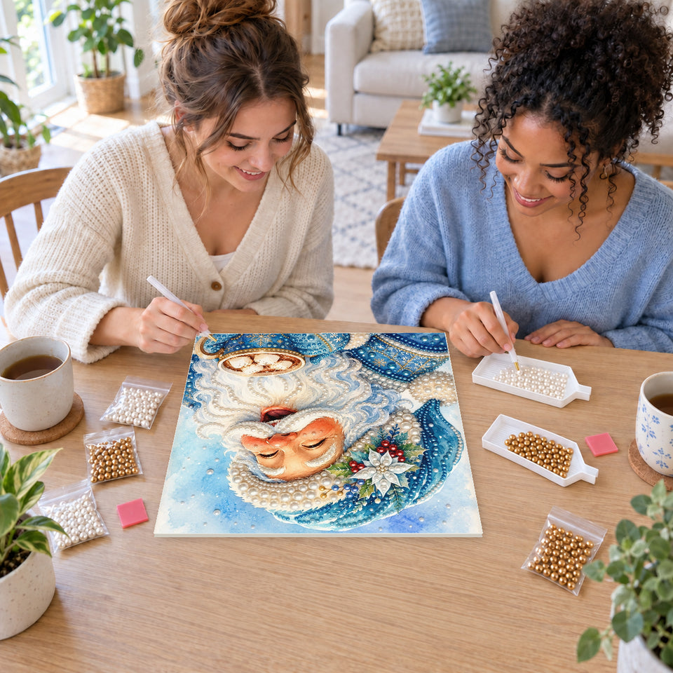 Two friends creating one shared Pearl artwork — Laughing Santa with a Blue Cocoa Mug. Pearl diamond painting DIY kit by Isuvio.