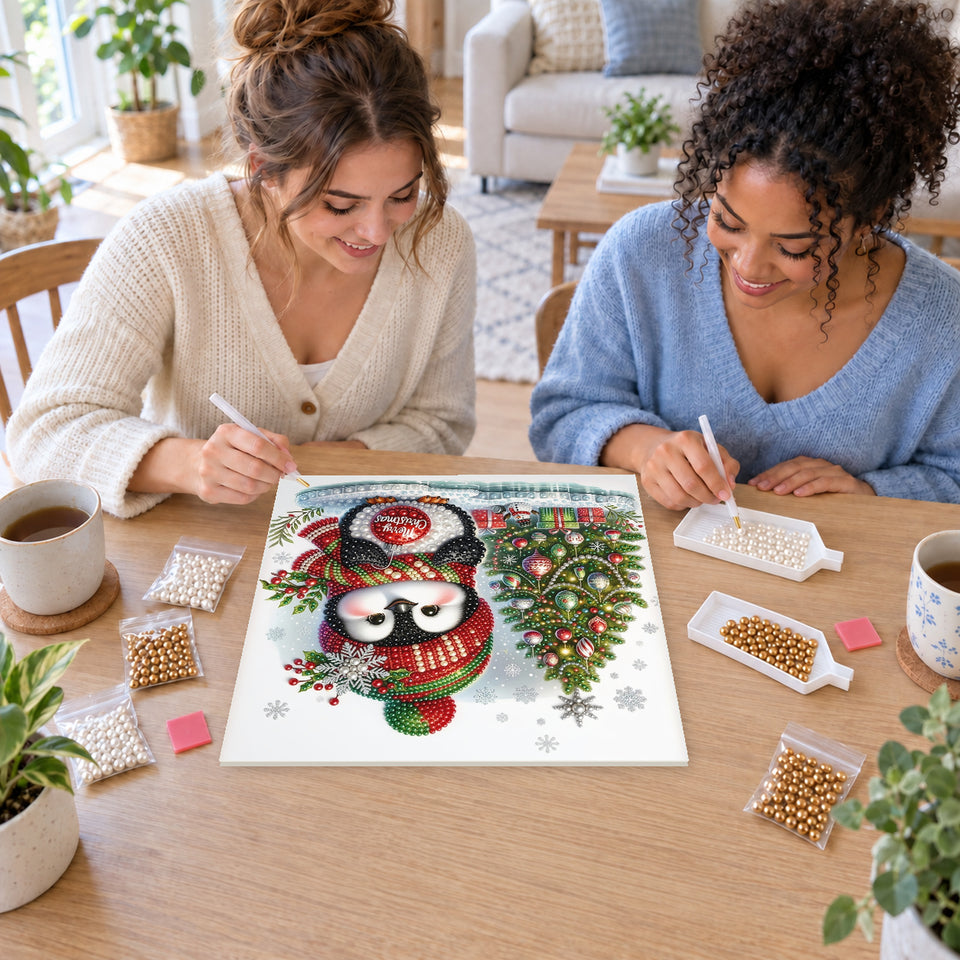 Two friends creating one shared Pearl artwork — Penguin with a Merry Christmas Bauble. Pearl diamond painting DIY kit by Isuvio.