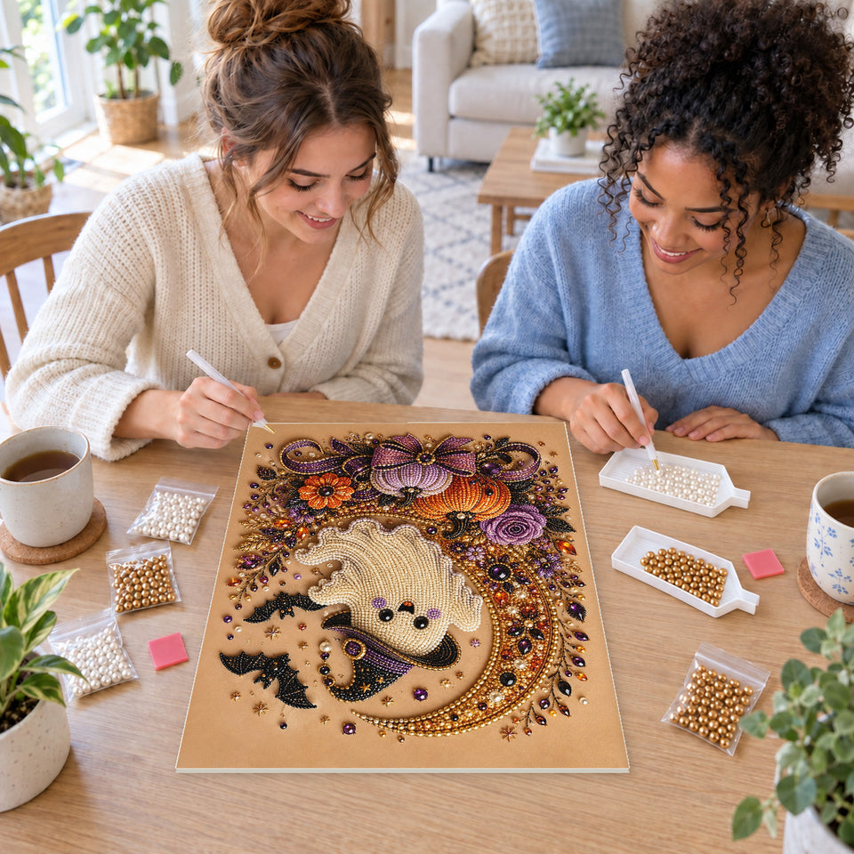 Two friends creating one shared Pearl artwork — Smiling Ghost on a Golden Crescent with Purple Pumpkins. Pearl diamond painting DIY kit by Isuvio.