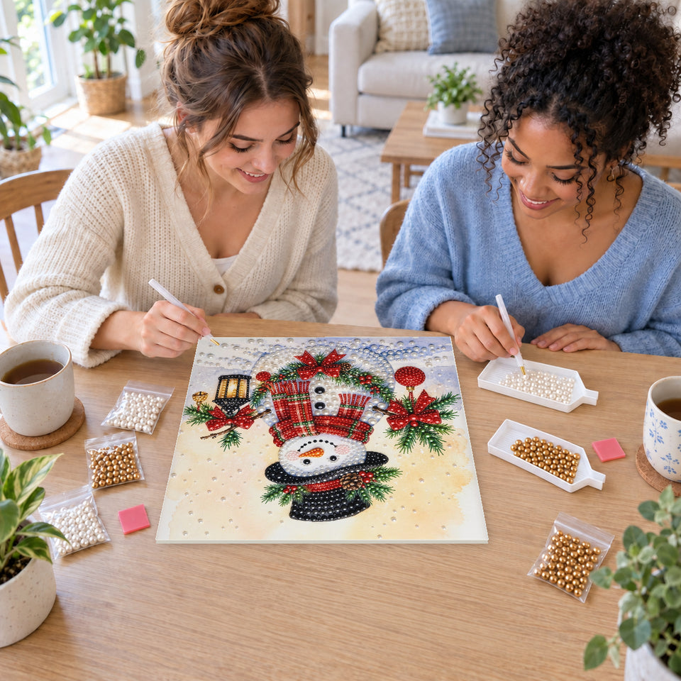 Two friends creating one shared Pearl artwork — Snowman with Holly and a Winter Lantern. Pearl diamond painting DIY kit by Isuvio.