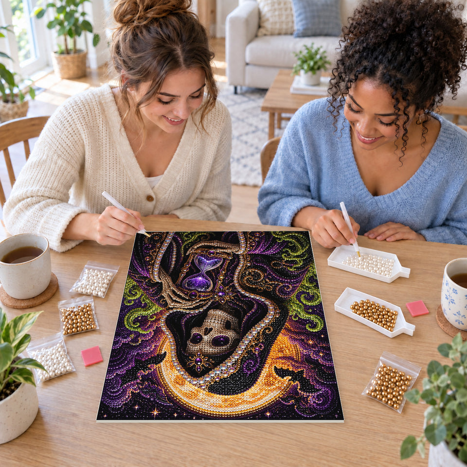 Two friends creating one shared Pearl artwork — Hooded Skeleton Holding a Purple Hourglass. Pearl diamond painting DIY kit by Isuvio.